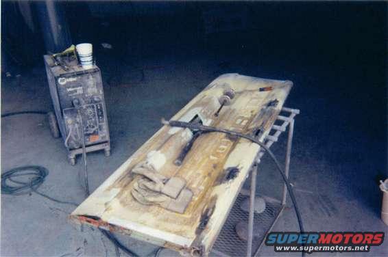 Truck door undergoing repair, with a Miller welder in the background