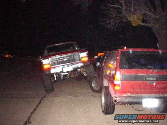 Red Ford Bronco and red Nissan Pathfinder parked next to each other at night