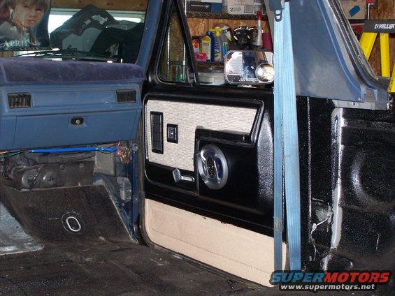 Interior door panel and dashboard of a blue truck, showing door insert with speaker grille and window controls