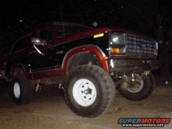 Red and black Ford Bronco with large tires, front 3/4 view