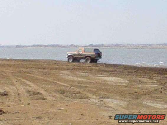 Tan SUV with spare tire on back, parked by water