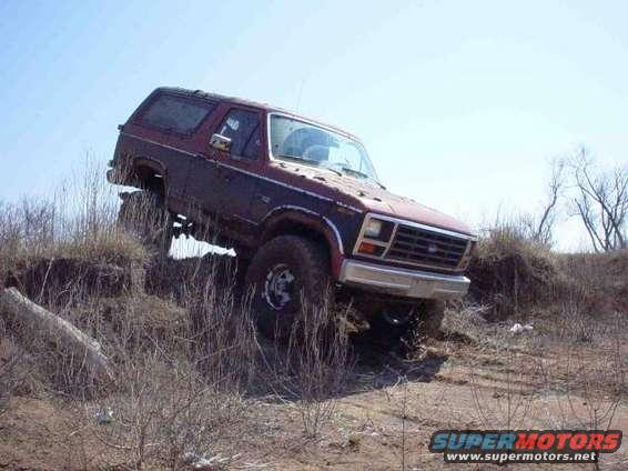 Ford Bronco climbing a dirt hill, tires kicking up dirt
