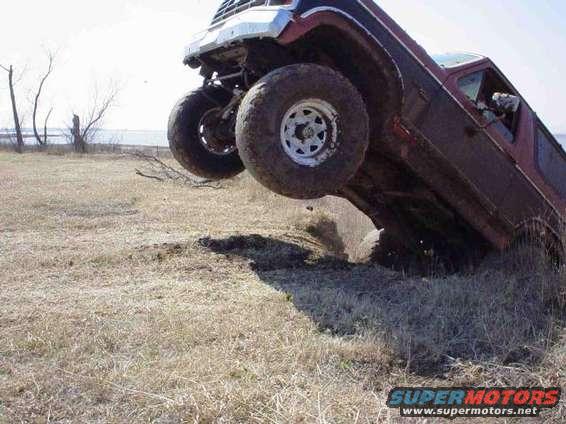 Red pickup truck tilted on its side off-roading