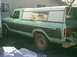 1979 Ford F-250 - A 1979 Ford F-250 pickup truck with a camper shell is parked next to a building.