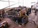1971 Ford Bronco - A man works on the front end of a yellow Ford Bronco in a garage.
