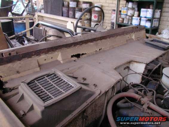 Interior of a vehicle showing dashboard, engine components, and a vent grille. Supermotors.net watermark visible