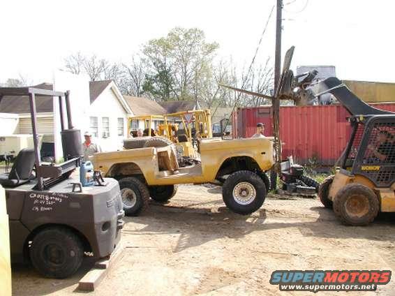 1971 Ford Bronco with doors removed, parked next to a forklift and a skid steer loader