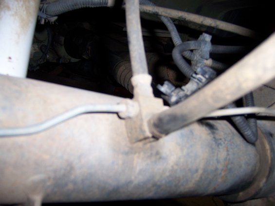 Underbody view of brake lines and suspension components with visible rust and dirt