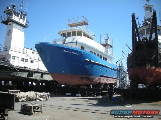Two large ships are in a dry dock area. One is blue with white superstructure and named ROBERT G. BROWNLIE. Another ship is to the right, mostly obscured