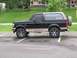 1990 Ford Bronco - Side profile of a black 1990 Ford Bronco with tan accents and a spare tire mounted externally.