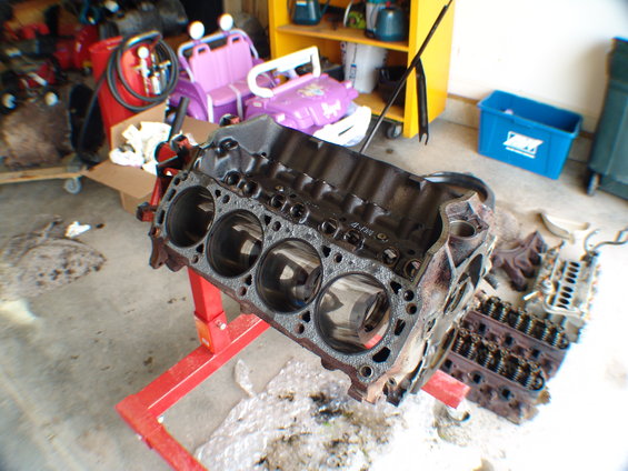 Engine block on red stand, with cylinder heads nearby