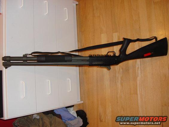 Shotgun with black stock and forend, resting on a white cabinet