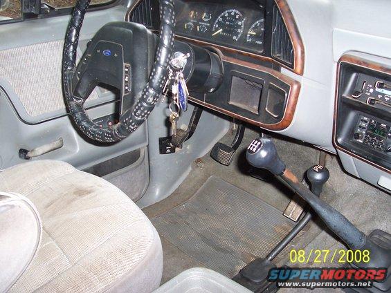 1988 Ford Bronco interior showing steering wheel, dashboard gauges, manual transmission shifter, and passenger seat