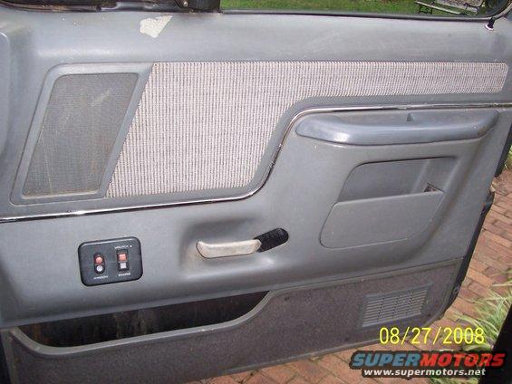 gray interior door panel with fabric insert, speaker grille, and power window controls