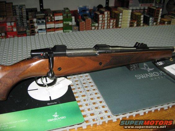 Rifle with wooden stock and metallic bolt action, on a Swarovski Optik mat