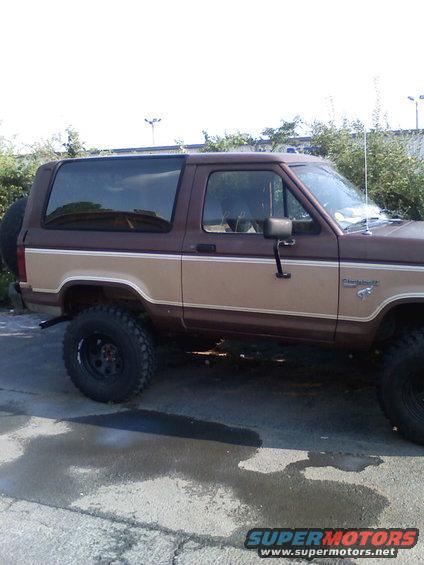 Brown and tan Ford Bronco II, lifted with off-road tires. Spare tire mounted on rear