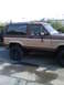1984 Ford Bronco II - Side view of a lifted Ford Bronco II with a two-tone paint job and a spare tire on the back.