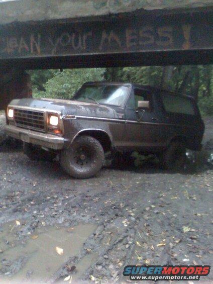 Muddy 1978 Ford Bronco stuck under a bridge with graffiti