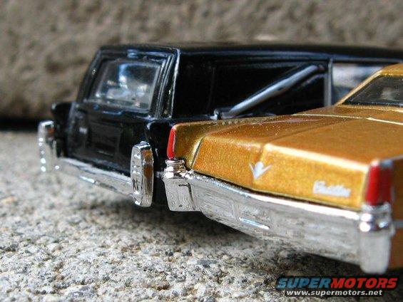 Rear view of a black toy hearse next to a gold toy Cadillac