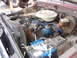 1979 Ford Bronco - The engine bay of a vehicle, a V8 engine, air cleaner, radiator, and battery, with visible hoses and wiring.