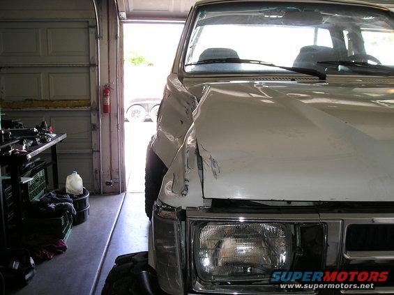 1986 Toyota Hilux with significant front-end damage, parked in a garage