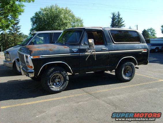 1978 Ford Bronco parked next to a van, showing rust on the hood