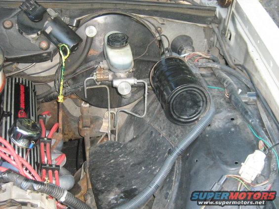 Engine bay showing brake master cylinder, oil dipstick, and black canister