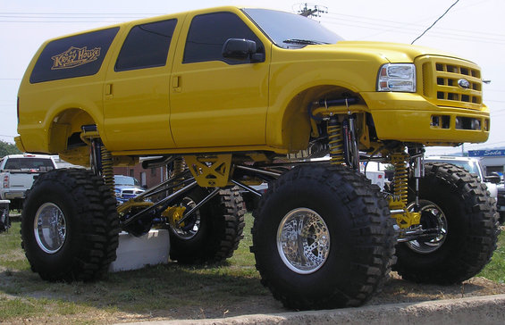 Yellow lifted SUV with monster truck tires and "Ketch House" logo on side
