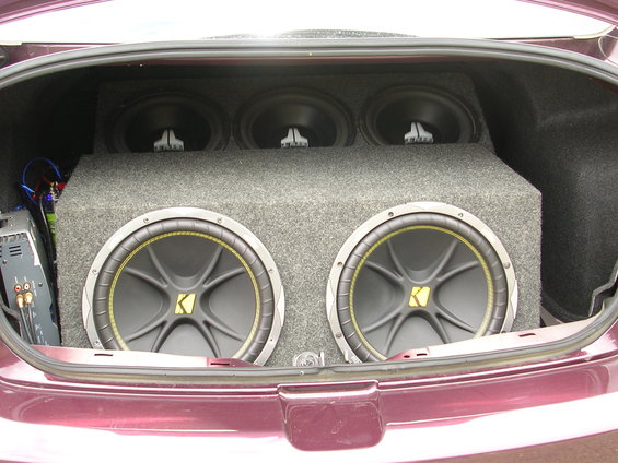 Car trunk with two large subwoofers in front and three smaller ones behind, plus an amplifier