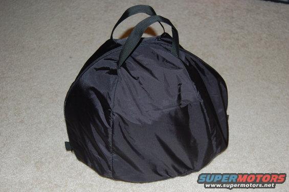 Black nylon helmet bag with two fabric handles on a carpeted floor