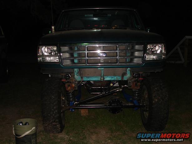 Front view of a lifted green Ford truck with a chrome grille and exposed suspension components