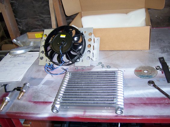 Transmission cooler and fan assembly on a workbench with tools and diagrams