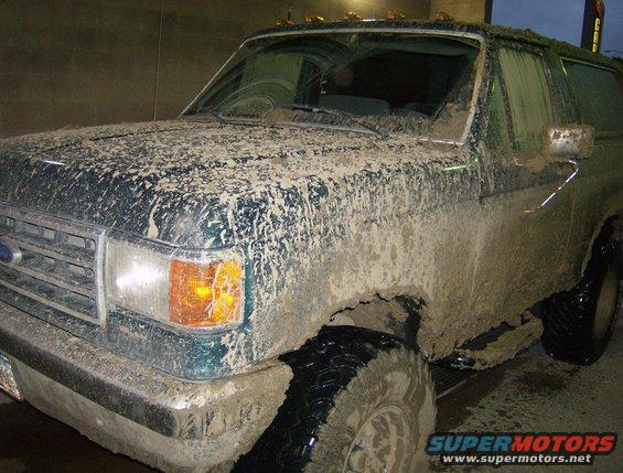 Mud-caked green SUV, looks like a Ford Bronco from the early 90s