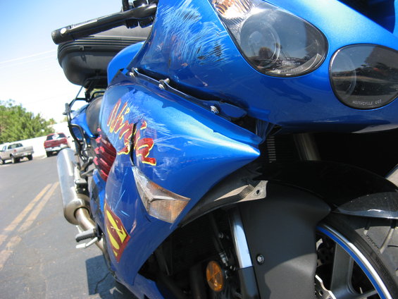 2007 Kawasaki Ninja motorcycle with significant scratches and dents on the blue fairing