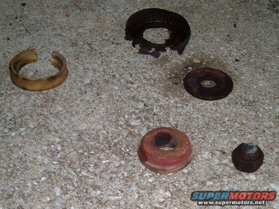 Various suspension parts including bushings and a nut on concrete