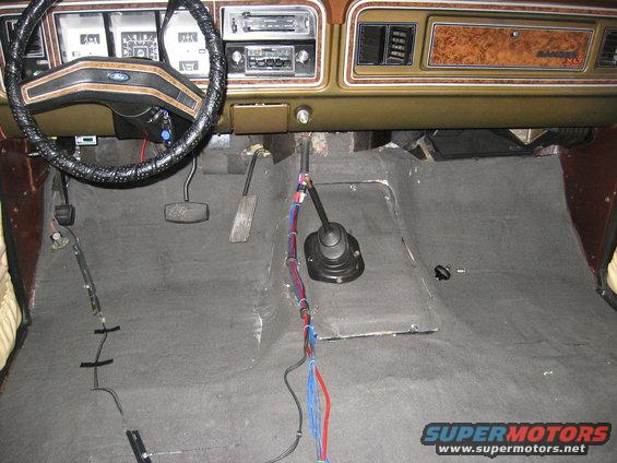 1979 Ford Bronco interior showing dashboard, steering wheel, floor shifter, and exposed wiring