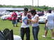 2009 Ford Mustang - A group of people gather at a car show, with several Ford Mustangs on display in the background.