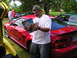 2009 Ford Mustang - Man reads Mustang Generations magazine next to a red Mustang with custom graphics at an outdoor car event.