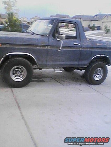 Side view of a dark blue 1978 Ford Bronco parked on a concrete driveway