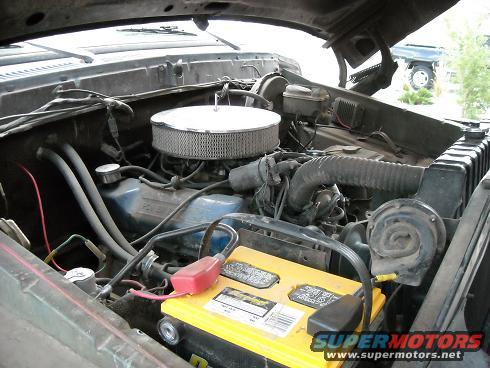 Engine bay of a 1978 Ford Bronco with a yellow battery and chrome air filter
