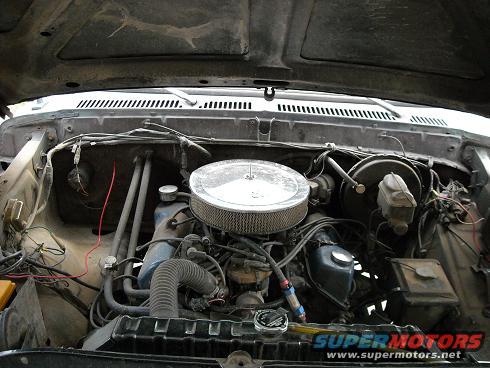 Engine bay with air cleaner, hoses, and brake booster visible