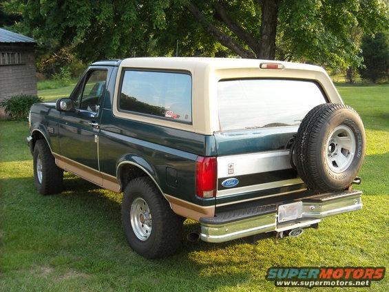 Green and tan 1994 Ford Bronco, rear quarter view with spare tire