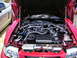 2009 Ford Mustang - Engine bay of a red car, extensive chrome detailing and a glimpse of another vehicle. The body style suggests a 2005 model year.