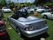 2009 Ford Mustang - A silver convertible Mustang is parked on grass with other vehicles and people around.