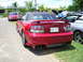 2009 Ford Mustang - A red convertible Mustang is parked next to other vehicles, showing its rear end and license plate.