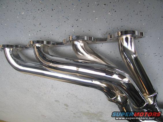 Chrome exhaust headers on a speckled gray floor