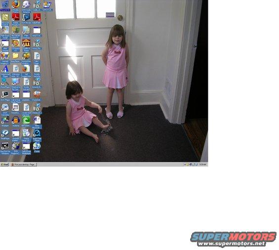 Two young girls in pink outfits stand and sit near a doorway. Desktop icons are visible on the left