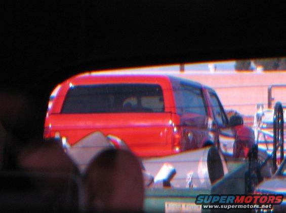 Red SUV with a cap, seen from behind. The body style suggests an 1980s model