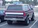 1996 Ford Bronco - Rear view of a lifted 1996 Ford Bronco in maroon and tan, parked in a lot.