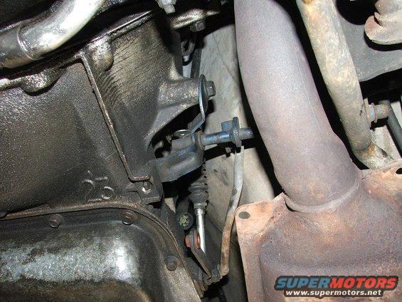 Undercarriage view of a vehicle's transmission and exhaust system, showing oily components and rust